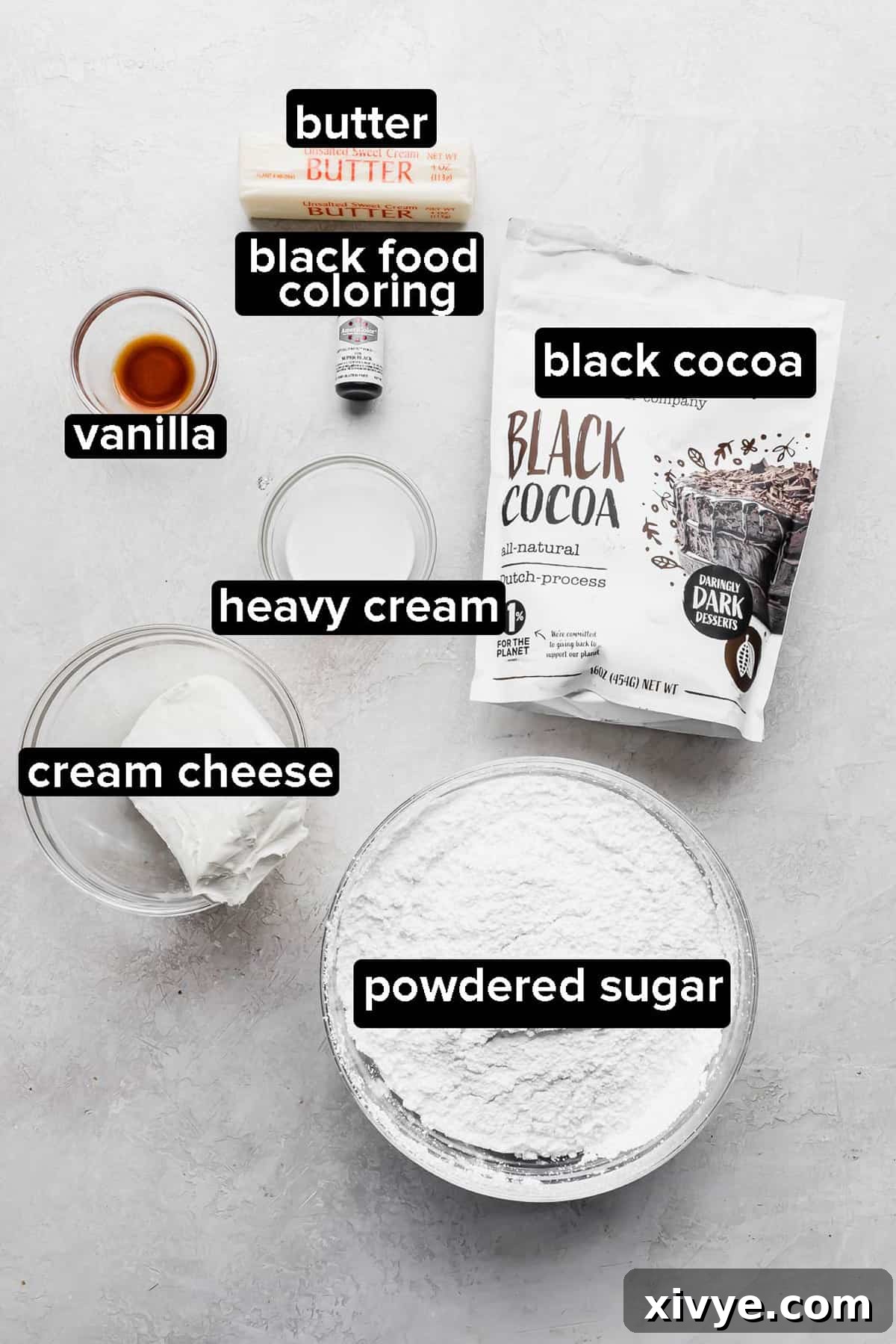 Key wet ingredients and frosting components for Black Velvet Cupcakes, such as cream cheese, butter, and black food coloring, arranged on a neutral gray background.