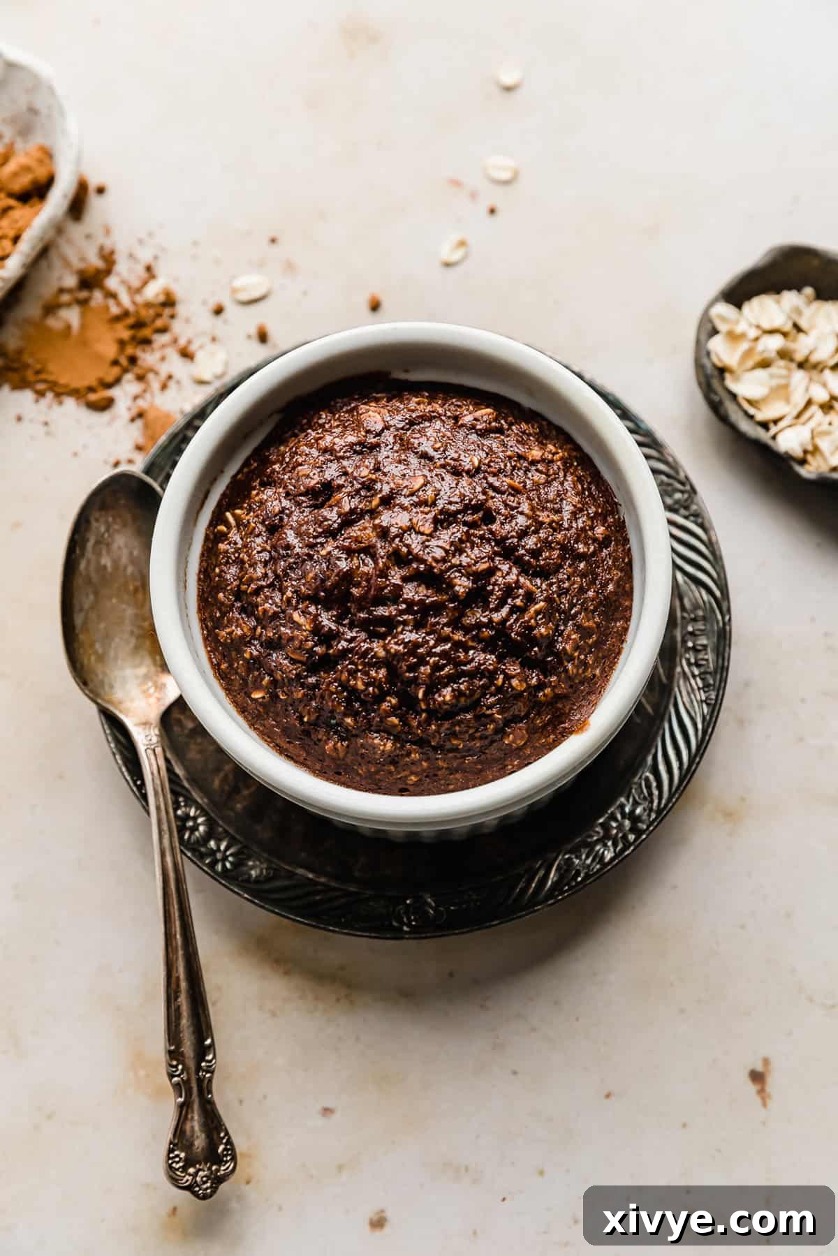 A serving of Chocolate Baked Oats in a white ramekin on a brown plate, ready to be enjoyed.