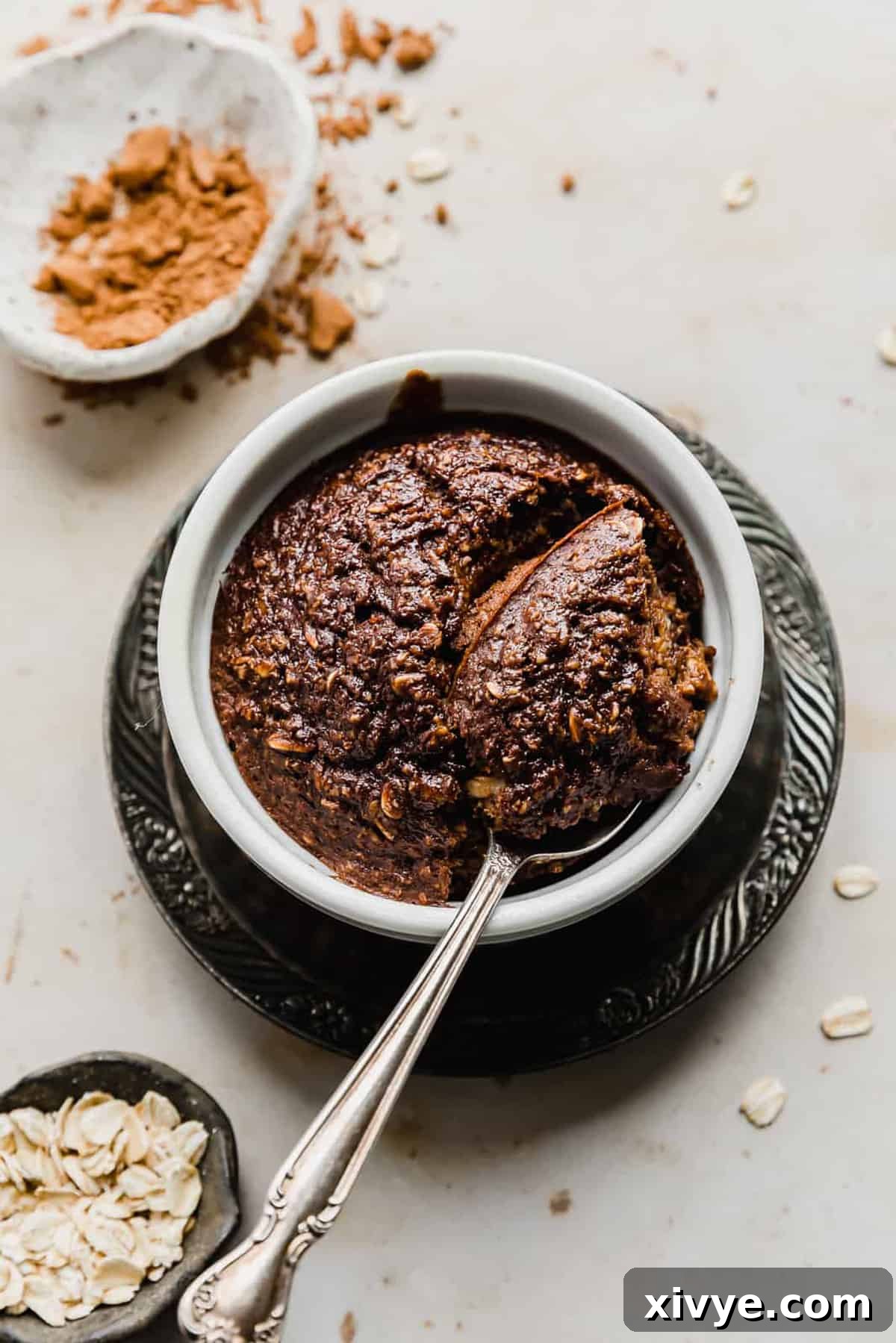 Chocolate Baked Oats in a white ramekin with a spoon scooping out some oats, showing the fluffy interior.
