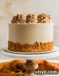 A Biscoff Caramel Cake on a marble cake stand, beautifully presented against a soft cream background.