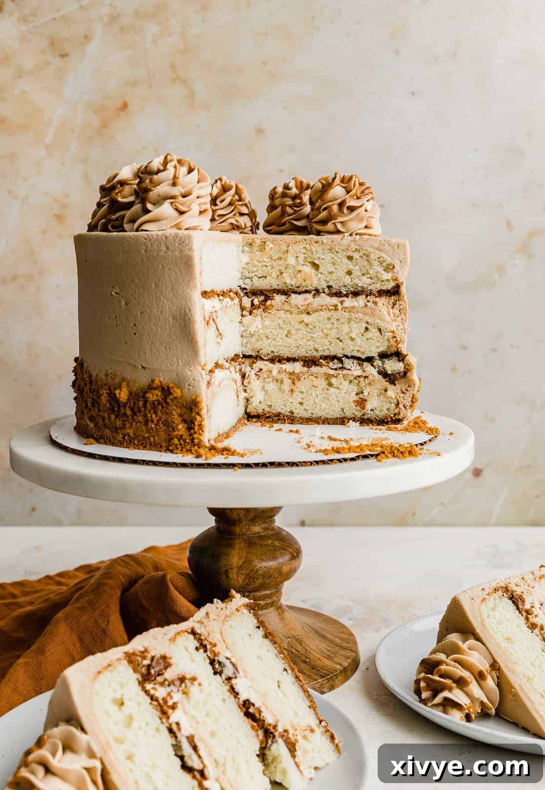 A visual representation of the three beautifully stacked layers of Biscoff Caramel Cheesecake Cake against a soft cream background.