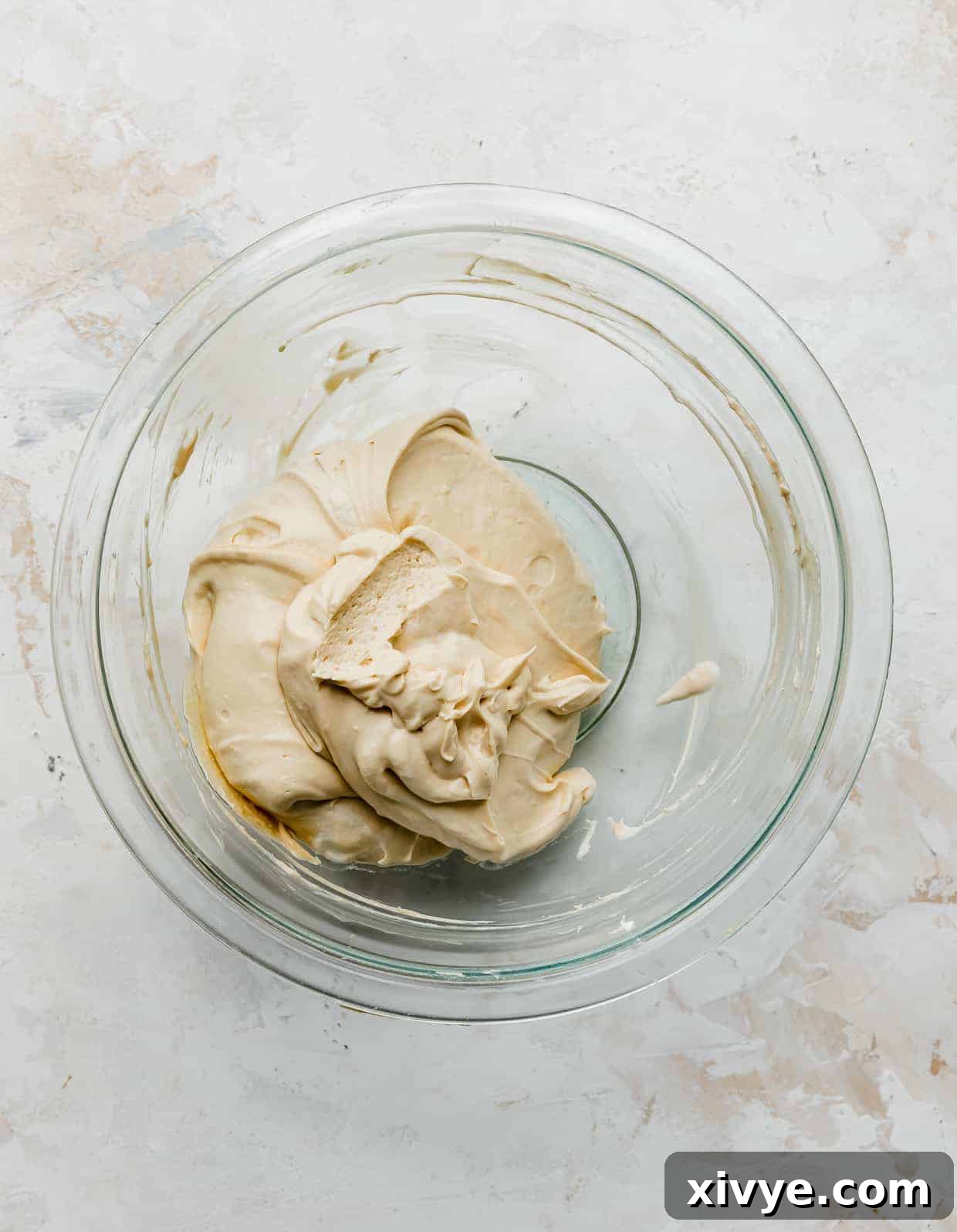 A glistening glass bowl filled with the velvety caramel cream cheese filling, ready to be layered into the Biscoff cake.