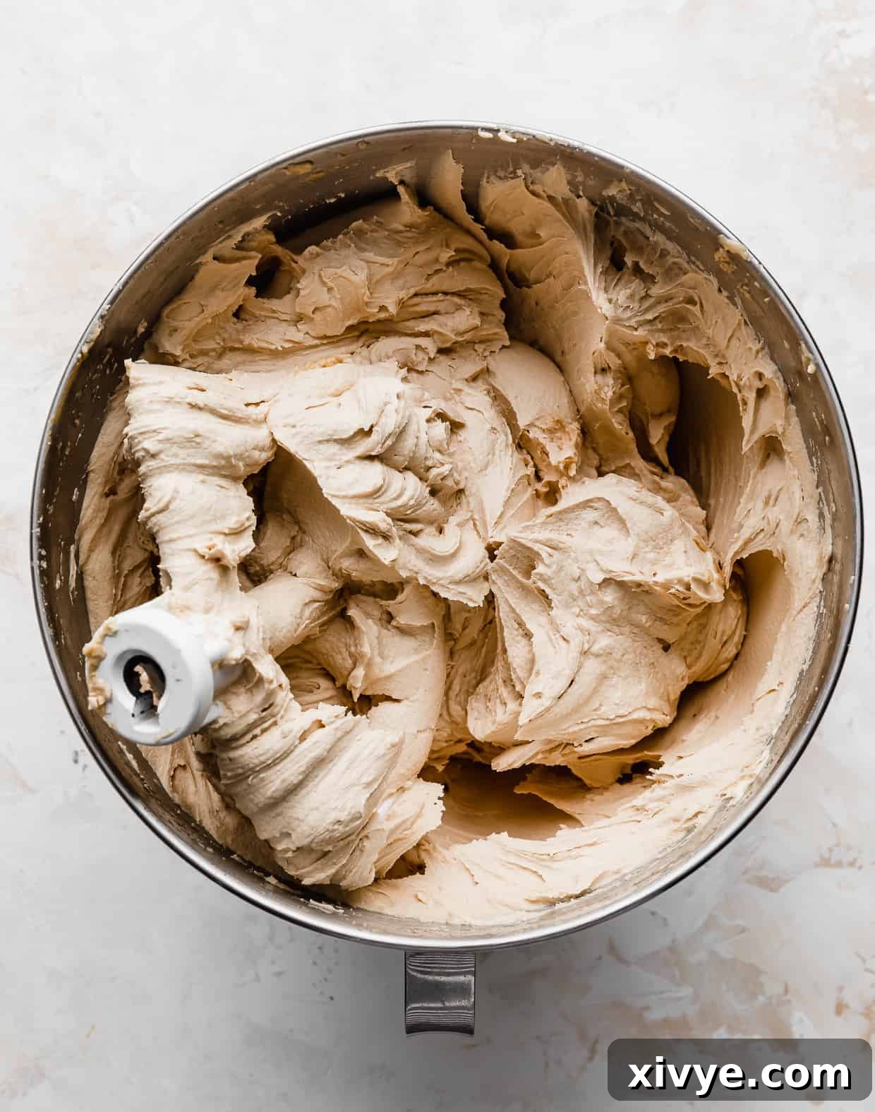 A metal mixing bowl showcasing the rich, creamy Biscoff cookie butter buttercream, perfectly whipped and ready for frosting.