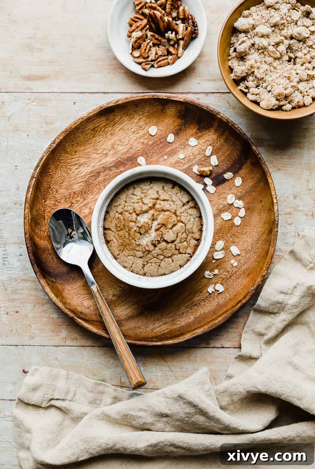 A ramekin with baked oats in it, on a wooden round plate, ready to be served.