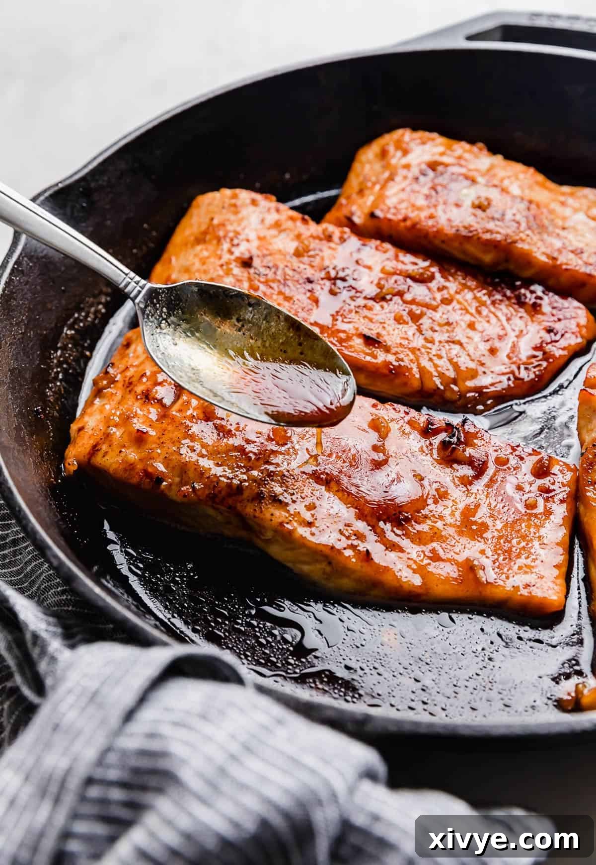 Sticky Honey Garlic Salmon 8 A spoon scooping rich brown juices over a perfectly cooked cast iron Honey Garlic Baked Salmon fillet.