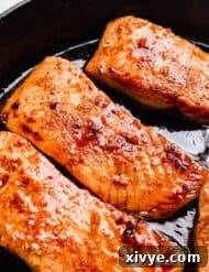 Sticky Honey Garlic Salmon 10 A close up photo of Honey Garlic Baked Salmon fillets in a black skillet, ready to serve.