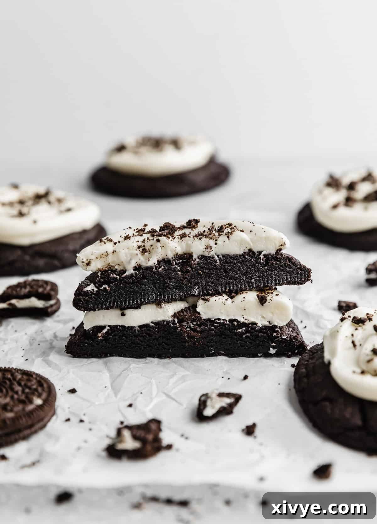 Giant Crumbl Style Chocolate Oreo Cookies 14 A Chocolate Oreo Crumbl Cookie cut in half on a parchment paper.