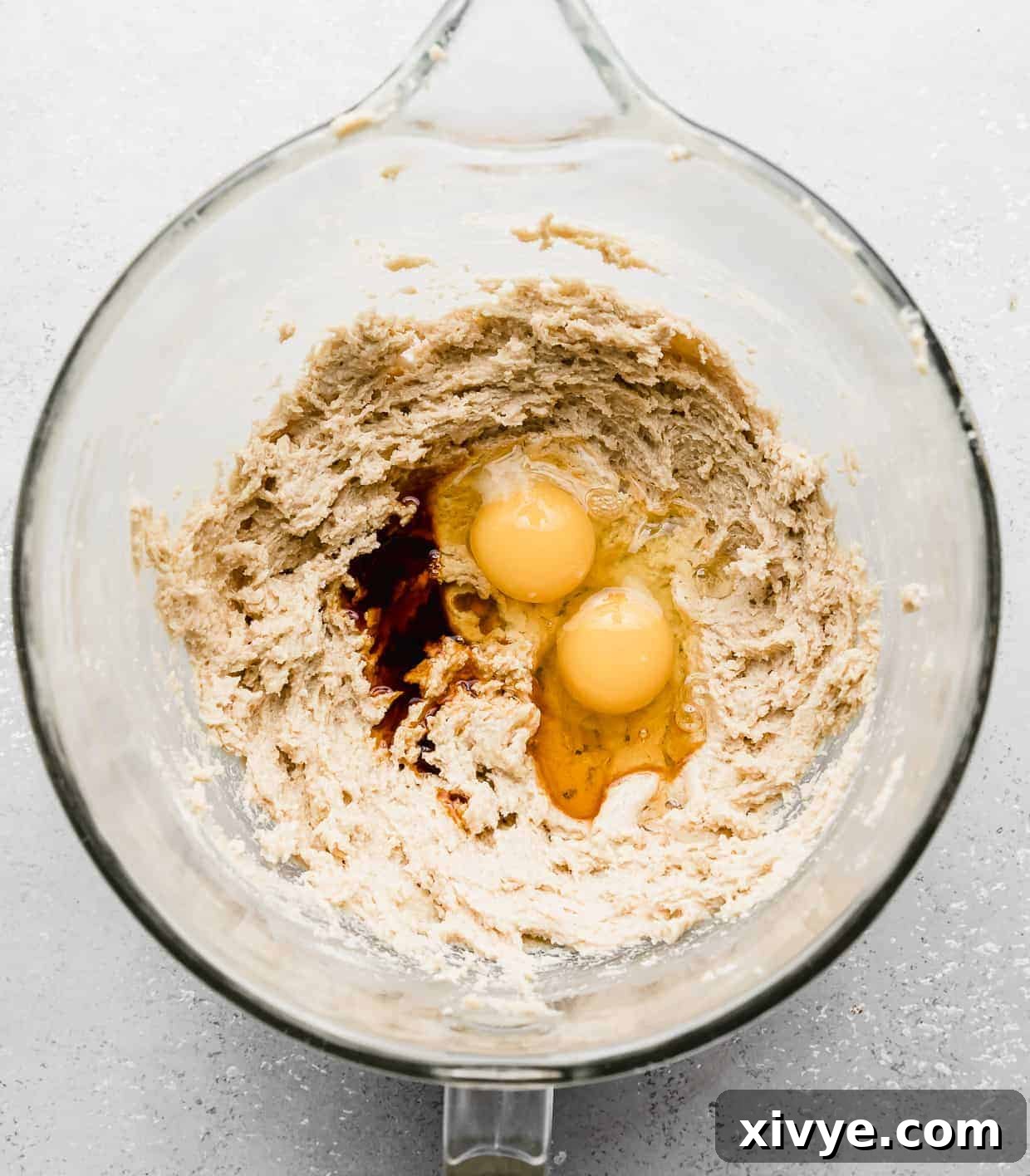 Giant Crumbl Style Chocolate Oreo Cookies 7 Two cracked eggs and vanilla extract in a glass mixing bowl.