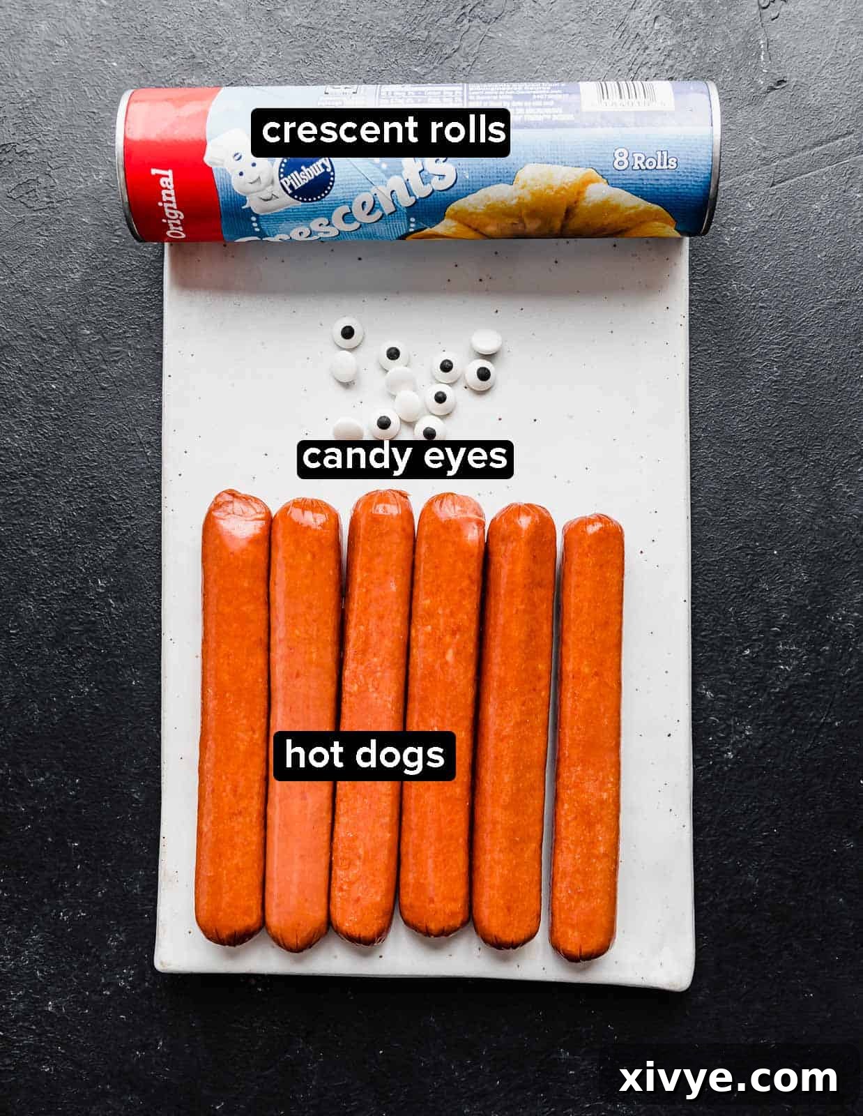 Creepy Canine Wraps 3 Mummy Hot Dogs ingredients on a rectangular white plate.