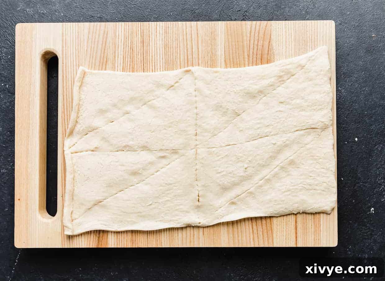 Creepy Canine Wraps 4 A wooden cutting board with an unrolled crescent roll sheet on it.
