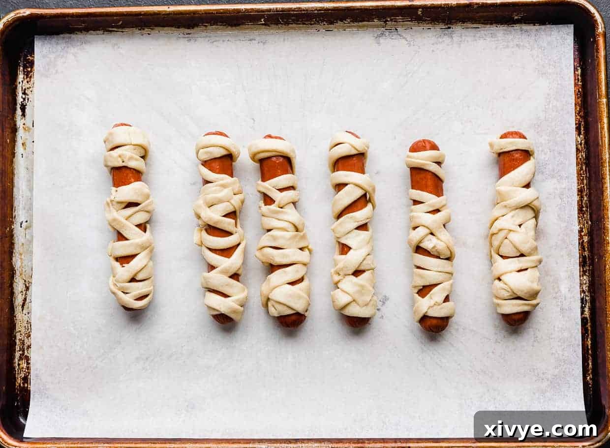 Creepy Canine Wraps 6 Hot dogs wrapped in crescent roll strips.
