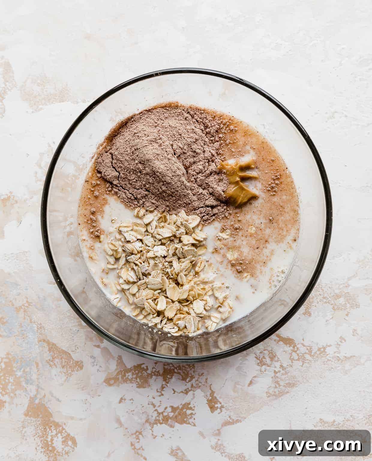 Powerhouse Protein Oats 4 A glass bowl full of oats, milk, peanut butter, and protein powder.
