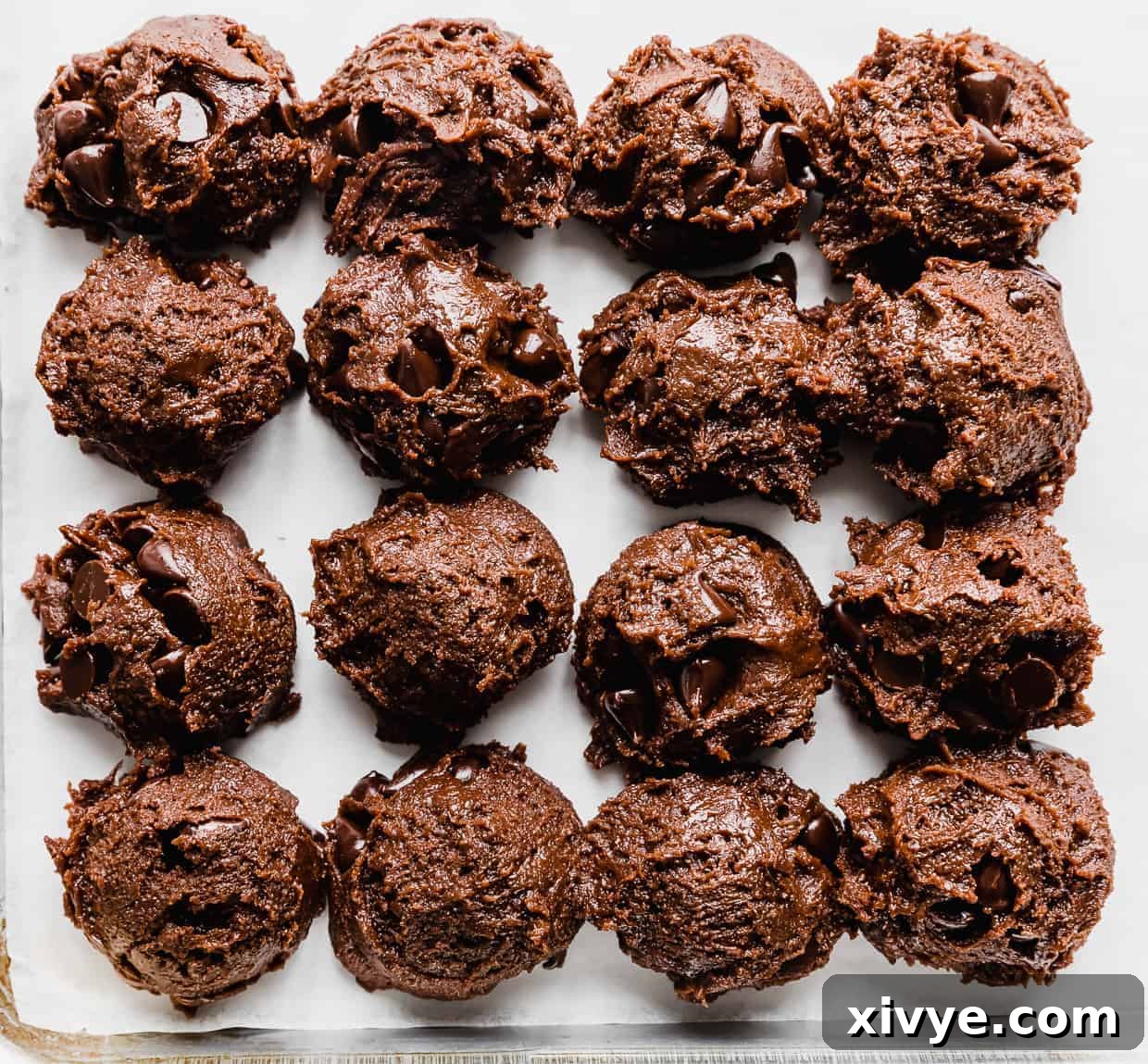 Double Chocolate Chip Cookie dough balls lined up on a white background, ready to bake.