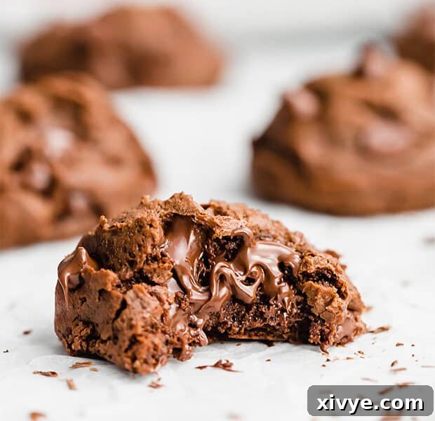 A close up photo of a bite taken out of a melty double chocolate chip cookie, showing its gooey center.