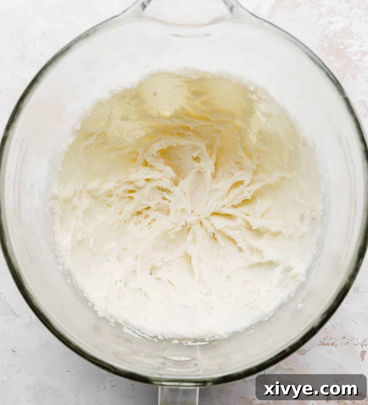 Creamed sugar and cream cheese in a glass mixing bowl.