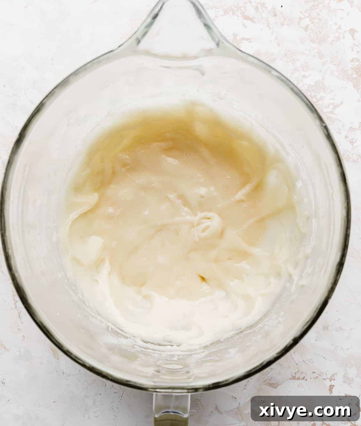 A white mixture in a glass mixing bowl, after wet ingredients are combined.