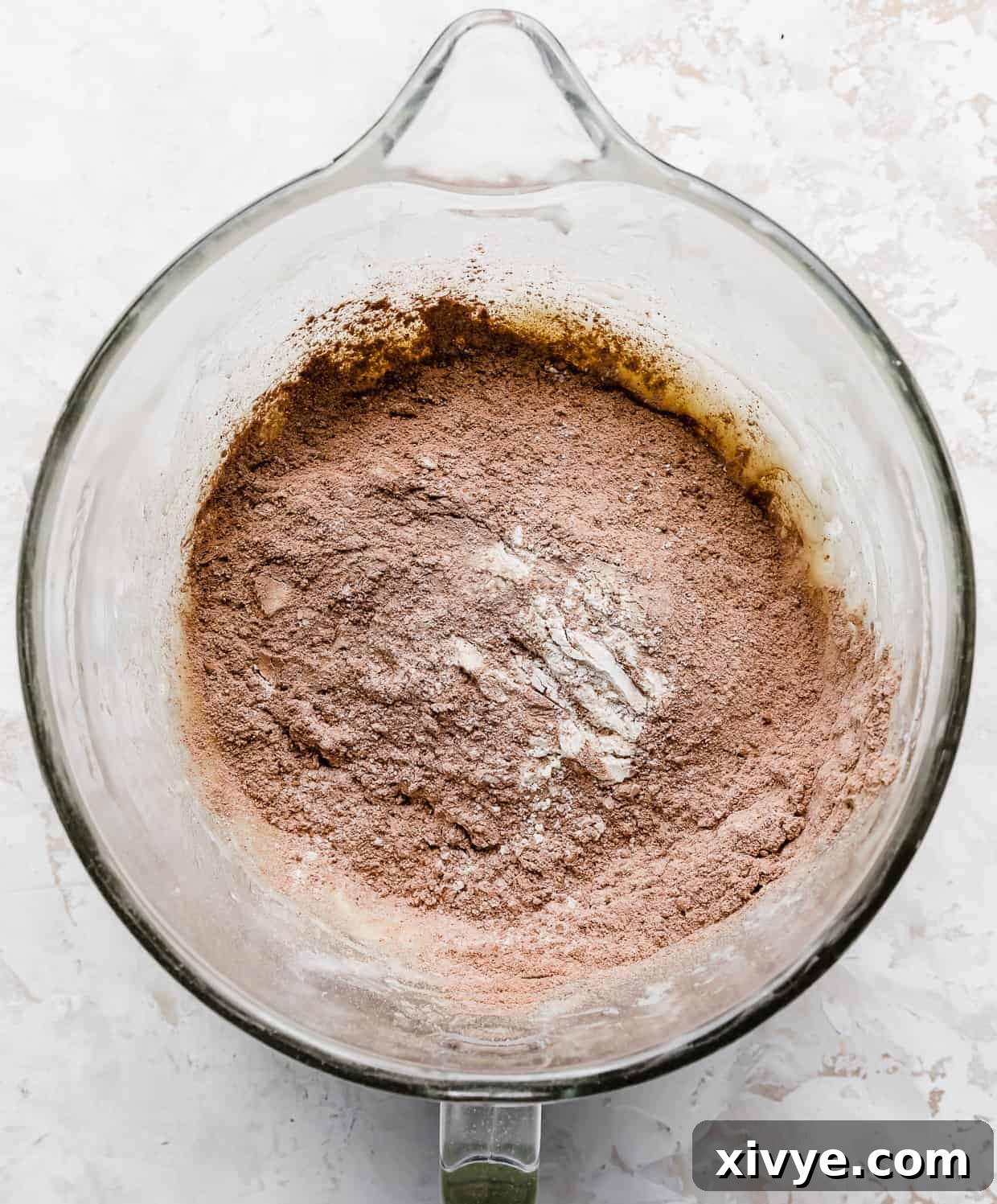 Cocoa powder mixed with flour in a glass stand mixer bowl, before adding wet ingredients.