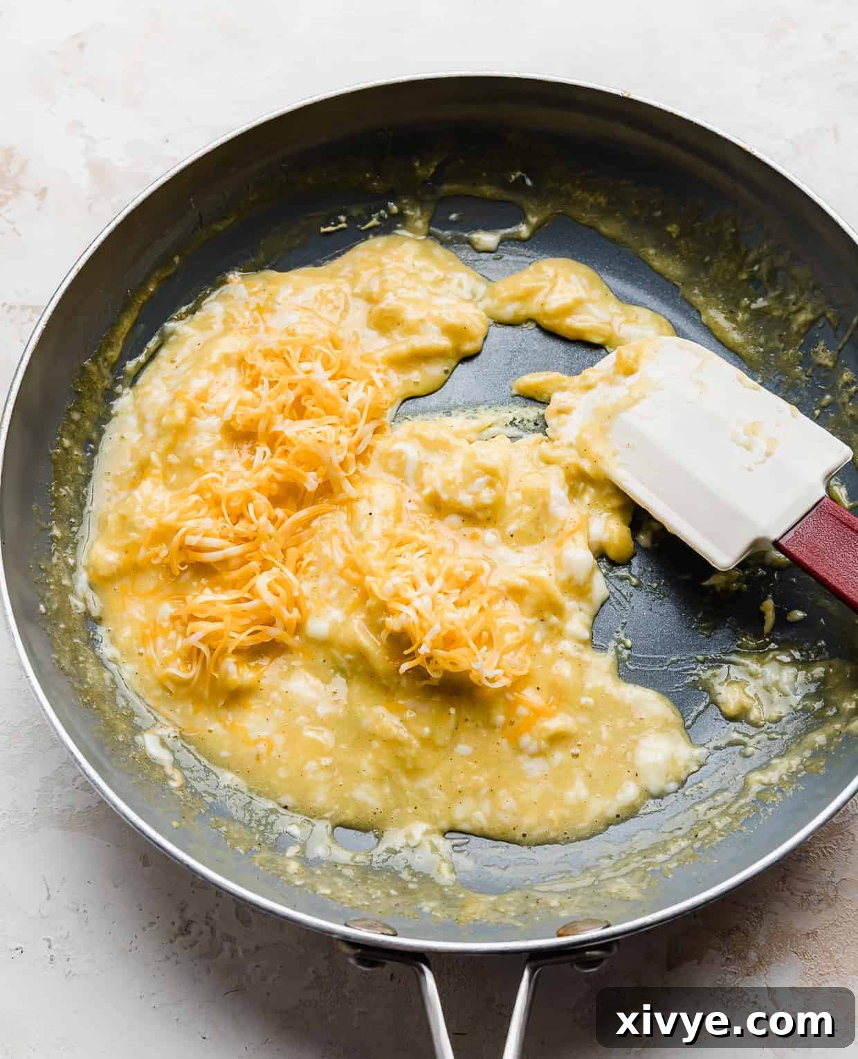 Gooey Cheese Scramble 7 Shredded cheddar cheese overtop scrambled eggs in a skillet, melting beautifully.