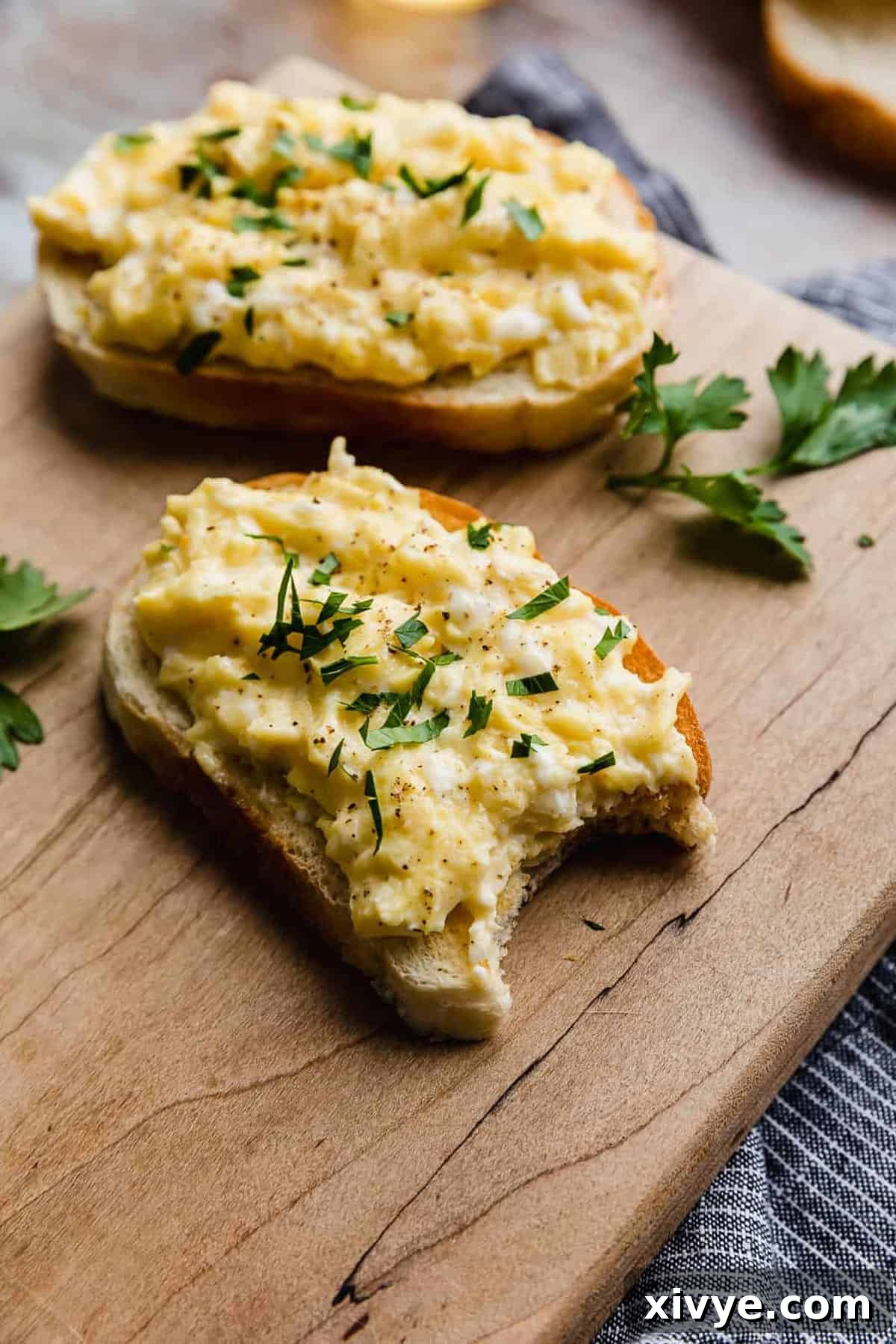  A piece of bread topped with scrambled eggs that's topped with parsley.
