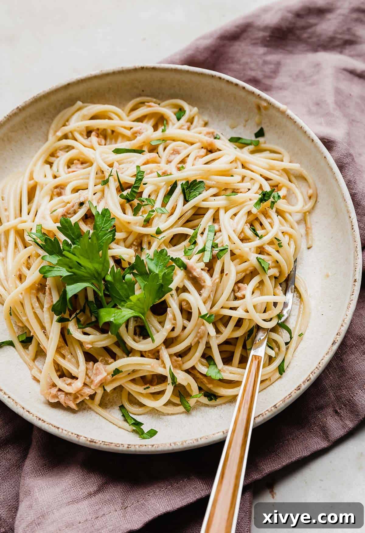 Tuna Carbonara on a white plate with a garnish of fresh parsley.
