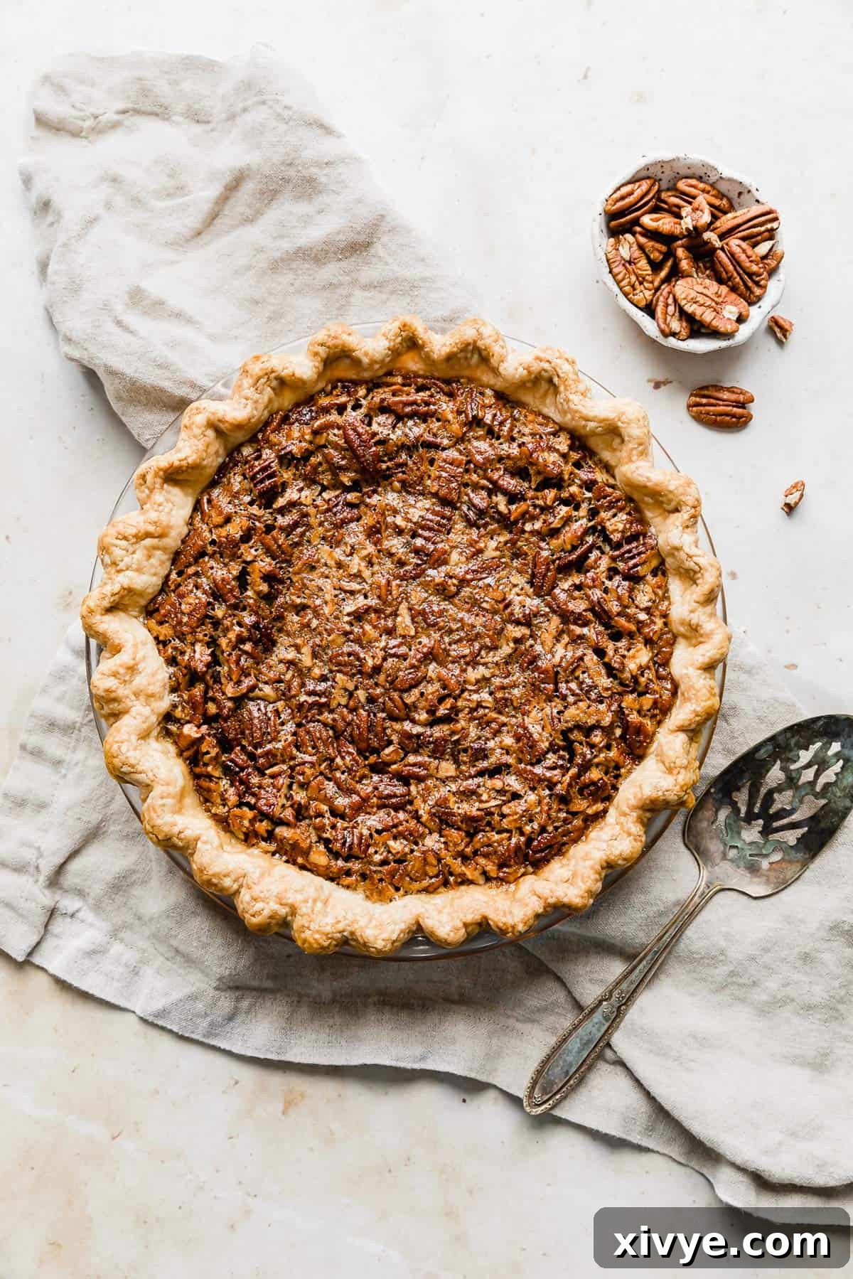 Ultimate Southern Pecan Pie 8 A baked Southern Pecan Pie on a tan colored linen.