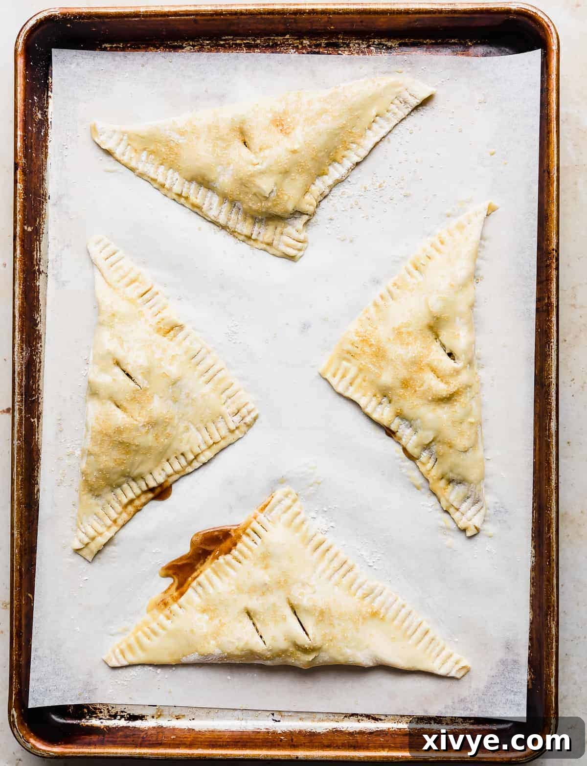 Unbaked Puff Pastry Apple Turnovers on a parchment lined baking sheet.