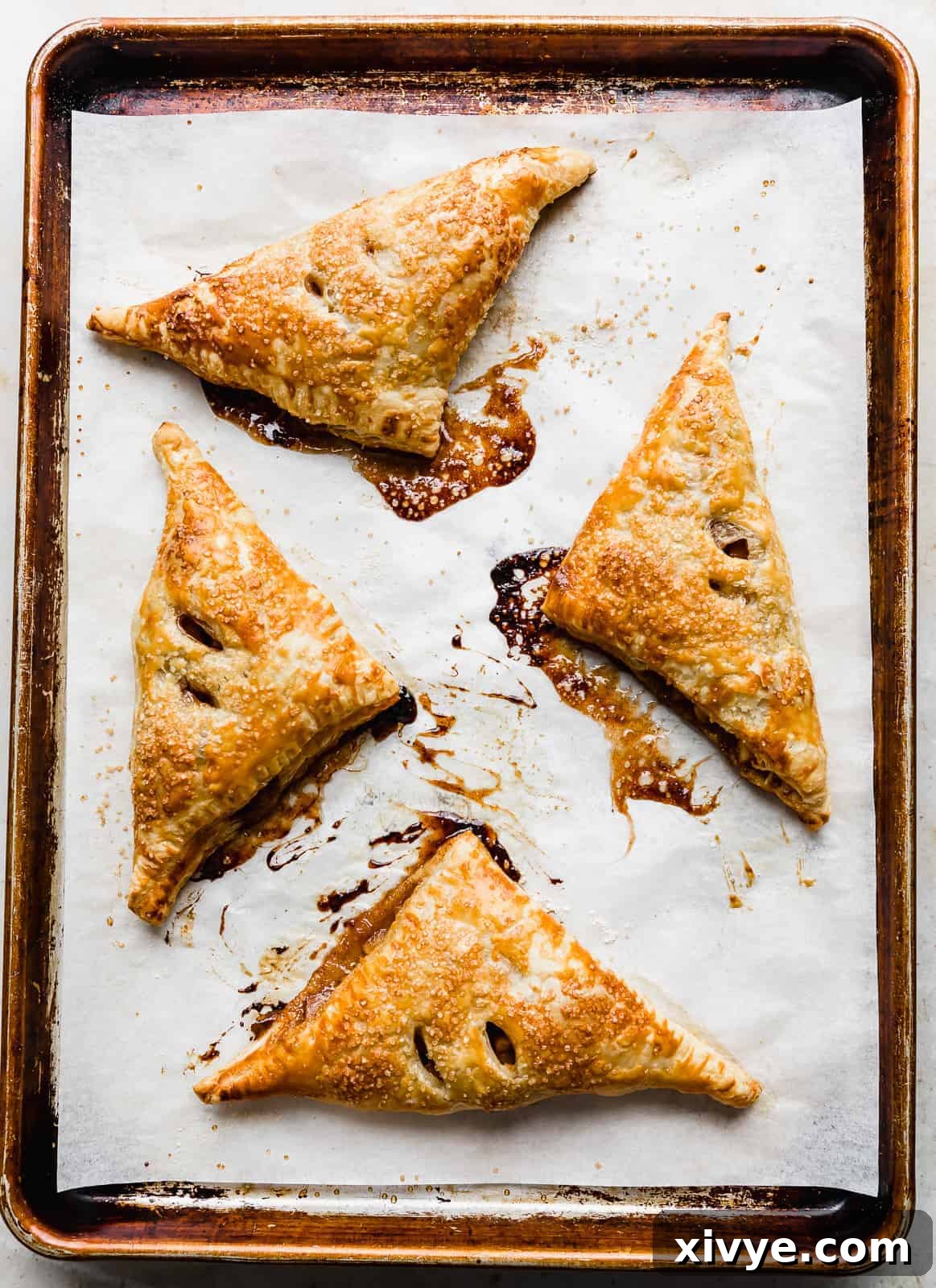 Golden brown Puff Pastry Apple Turnovers on a parchment lined baking sheet.