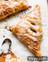 A glazed Puff Pastry Apple Turnover on a white parchment paper.