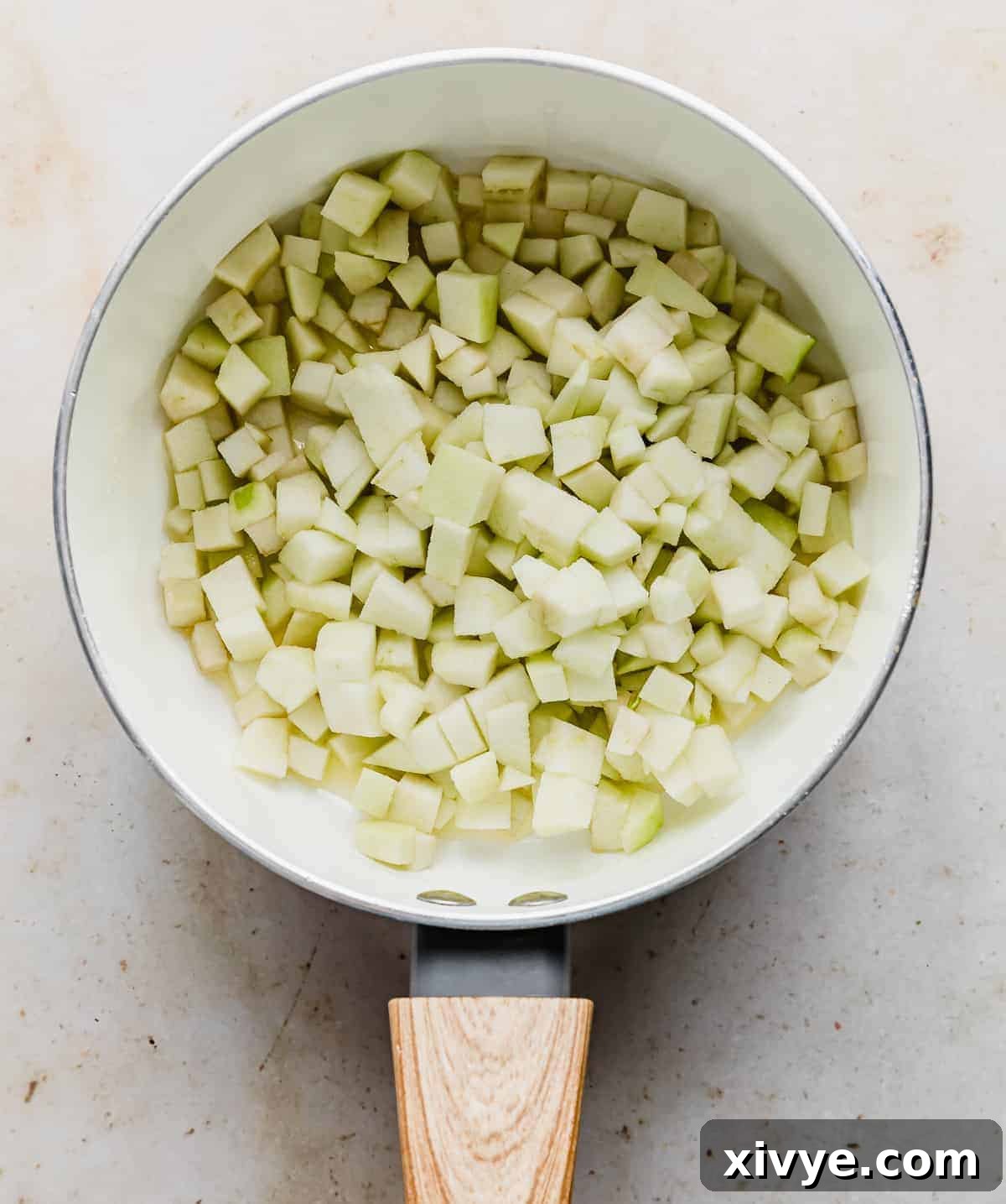 Diced apples in a white saucepan.