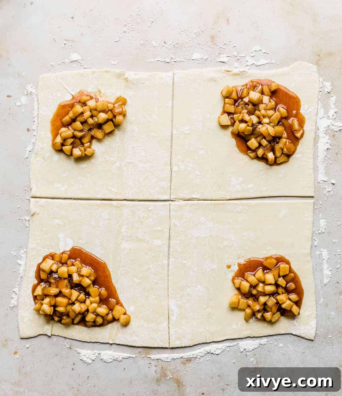 Squares of puff pastry topped with a brown diced apple mixture in one corner of each square.