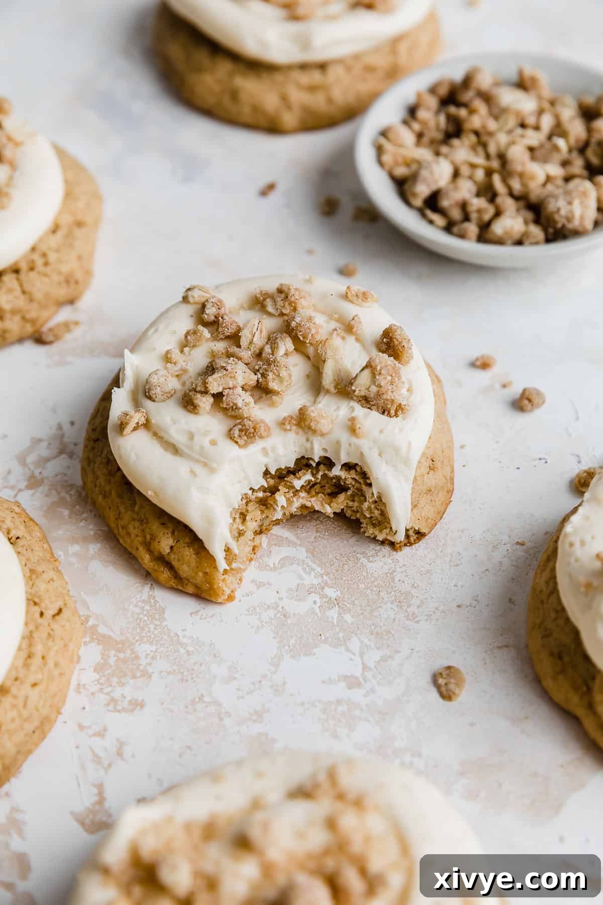 Gooey Caramel Apple Cookies 3 A bite taken out of a caramel apple flavored cookie that's topped with a caramel frosting and homemade streusel.