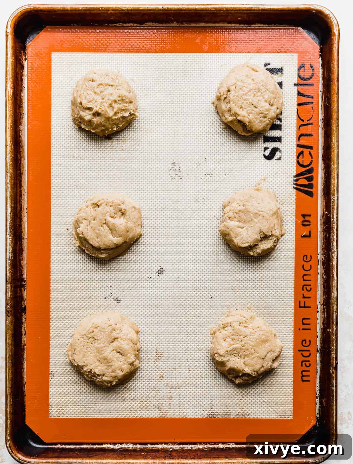 Gooey Caramel Apple Cookies 5 A baking sheet with six unbaked Caramel Apple Cookie dough balls on it.