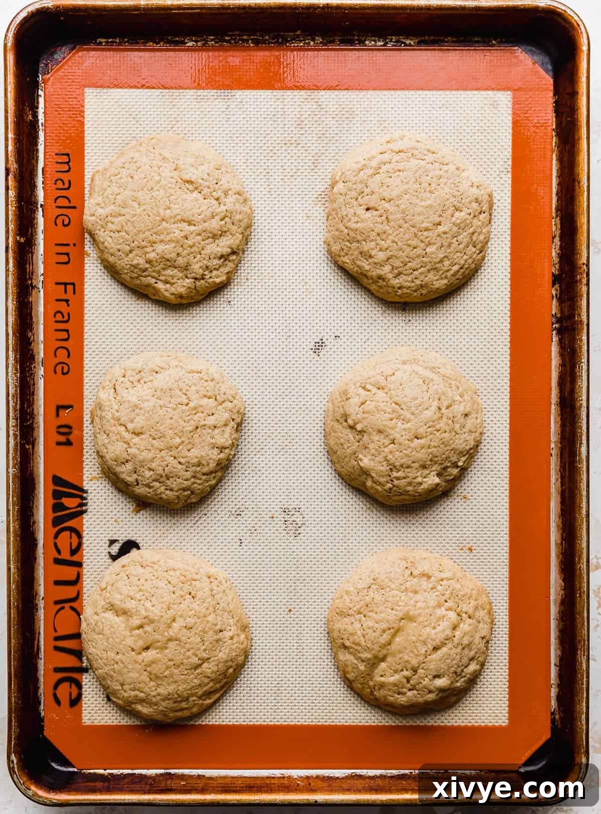 Gooey Caramel Apple Cookies 6 Six baked caramel apple cookies on a baking sheet.