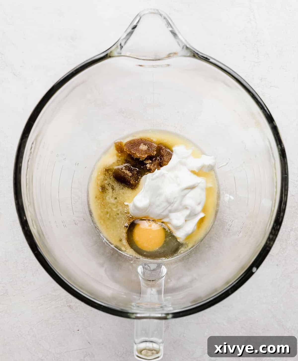 A glass bowl with sour cream, egg, and vanilla in it.