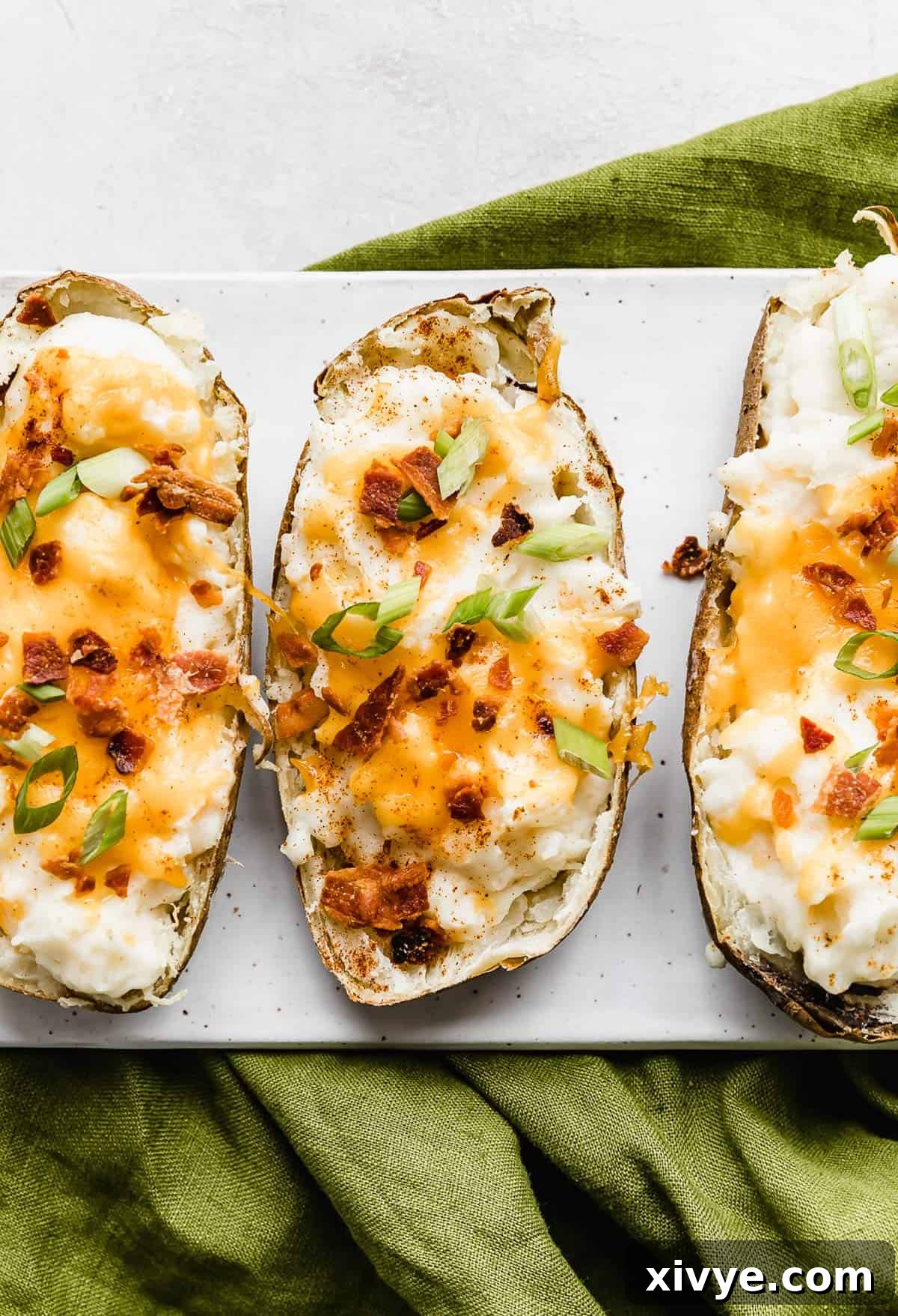 Decadent Double-Baked Potatoes 2 Three twice baked potatoes with cream cheese topped with cheese, green onions, and bacon.
