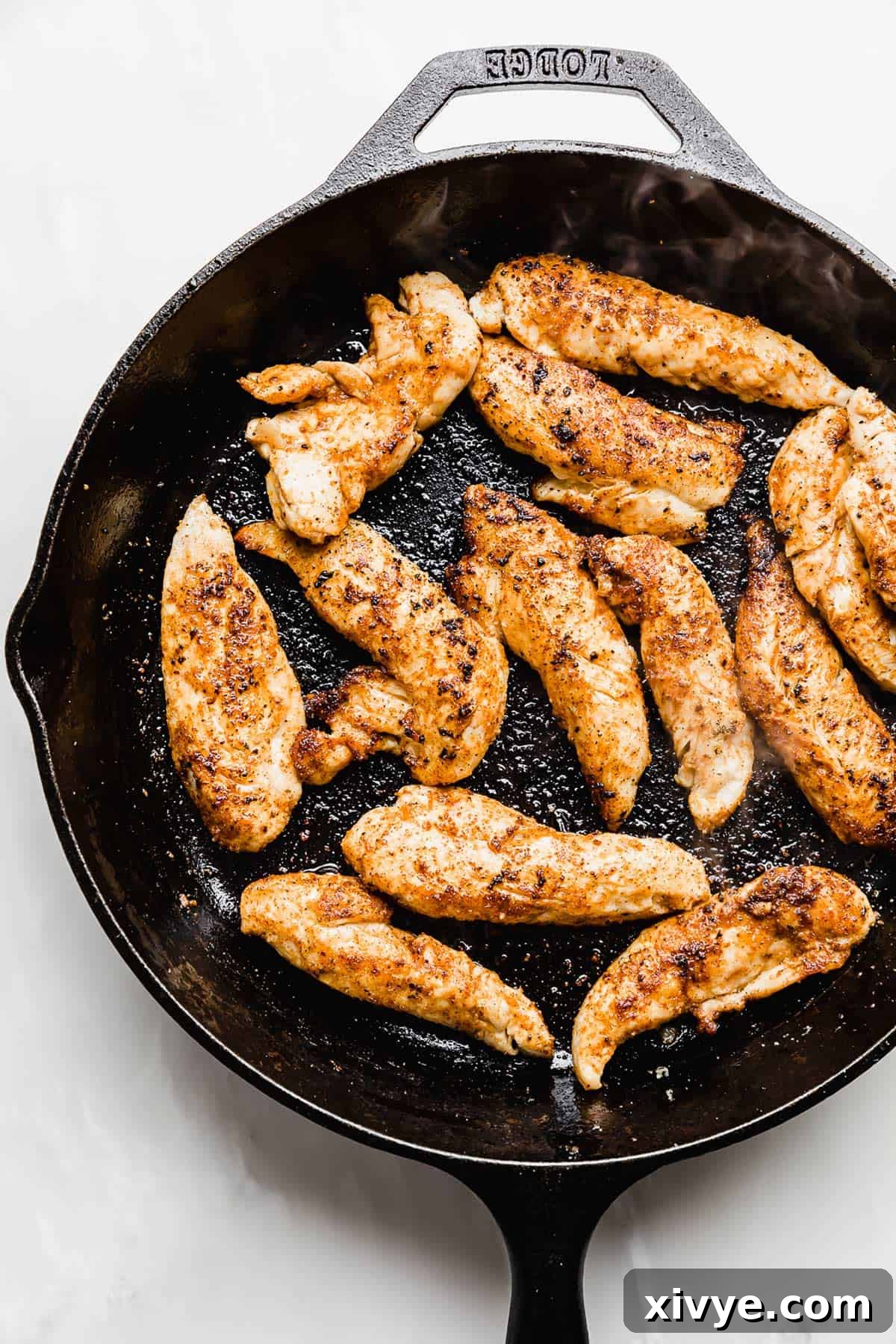 Browned chicken tenders in a cast iron skillet.