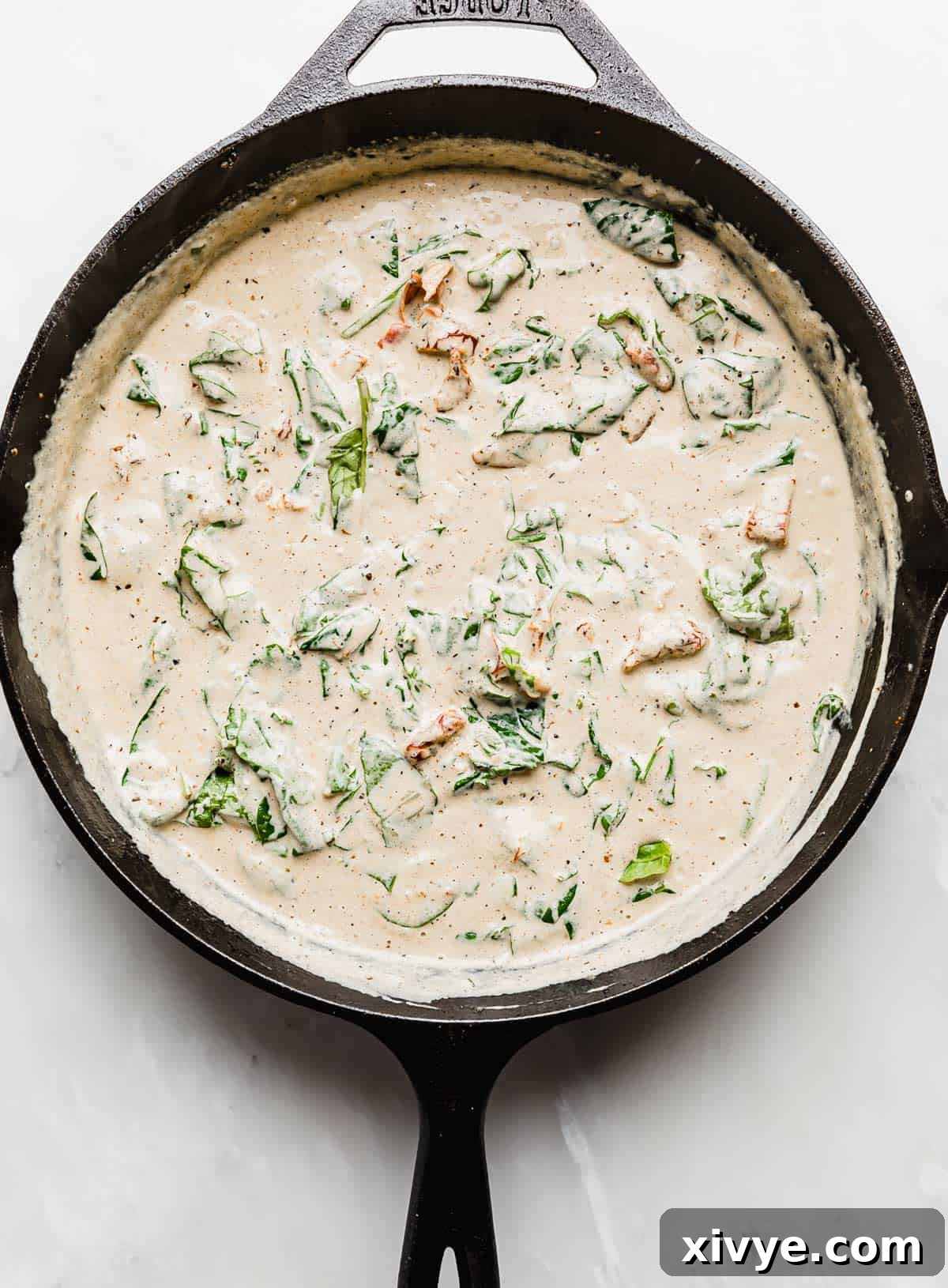 Creamy Tuscan Chicken gravy with spinach in a cast iron skillet.