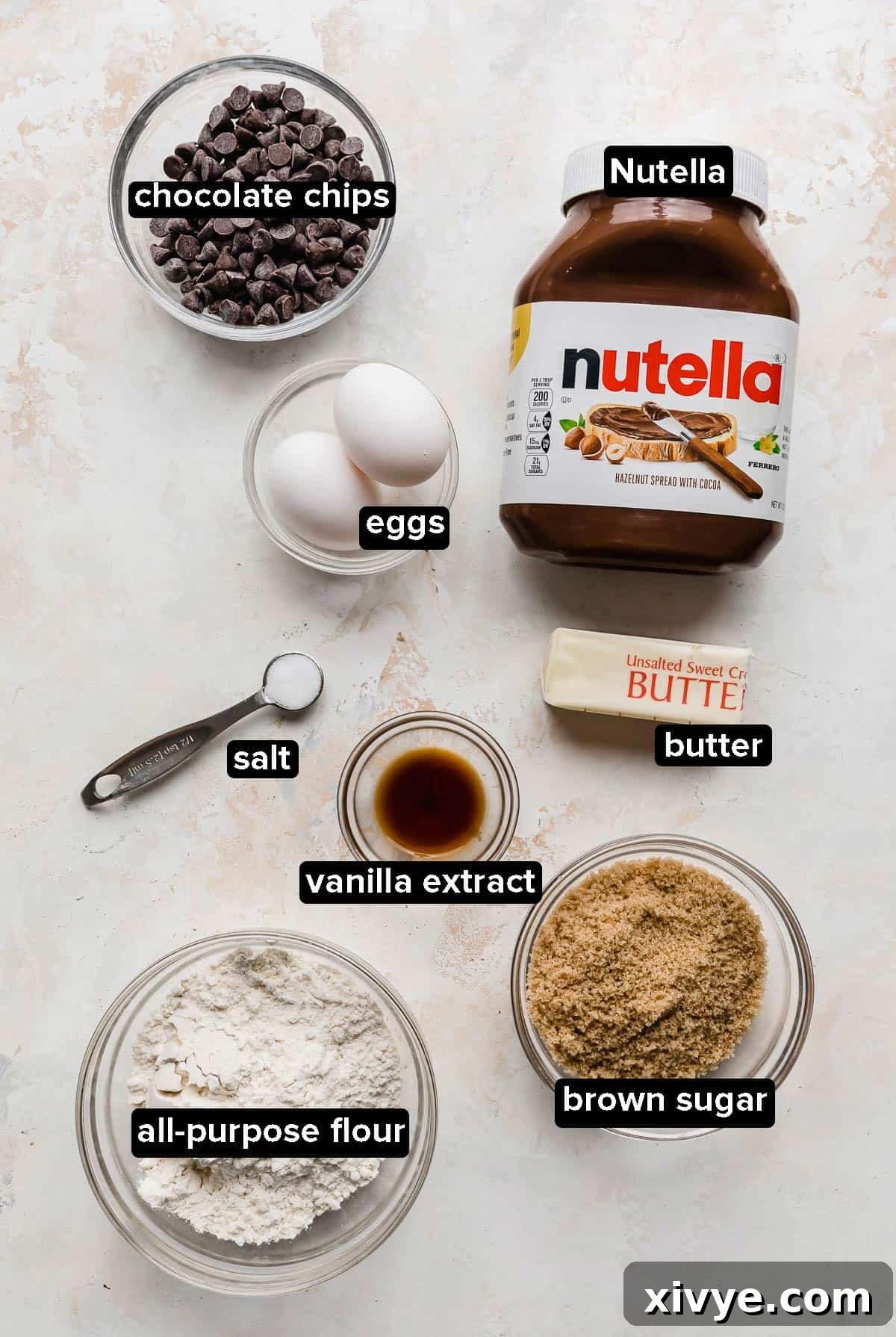 Decadent Nutella Hazelnut Brownies 3 Nutella Brownie ingredients laid out on a white textured background, ready for baking.