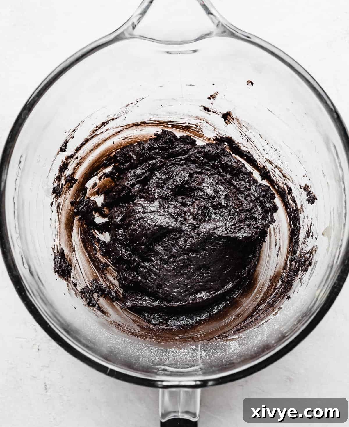 Thick, dark Oreo Donut batter in a glass mixing bowl, showcasing its rich black cocoa color.
