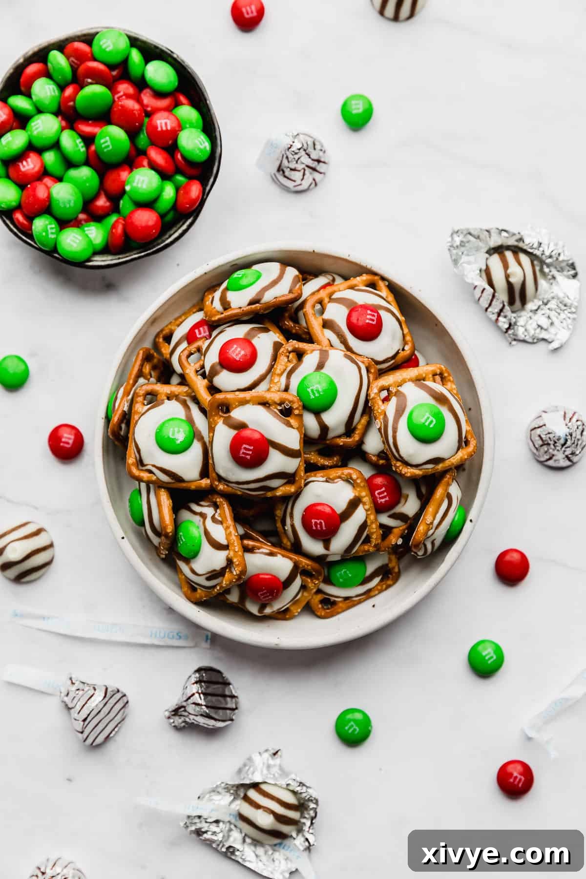 Yuletide Pretzel Bites 2 A crisp white plate holds a delightful stack of Christmas Pretzel Hugs, beautifully arranged on a clean white background, showcasing their festive red and green M&M toppings.