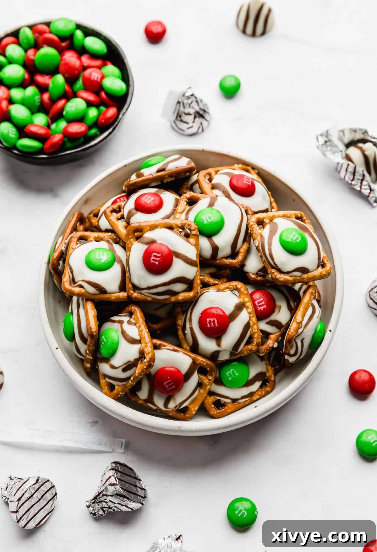 Yuletide Pretzel Bites 6 A charming white bowl overflowing with beautifully crafted Christmas Pretzel Hugs, set against a pristine white background, ready to be enjoyed.