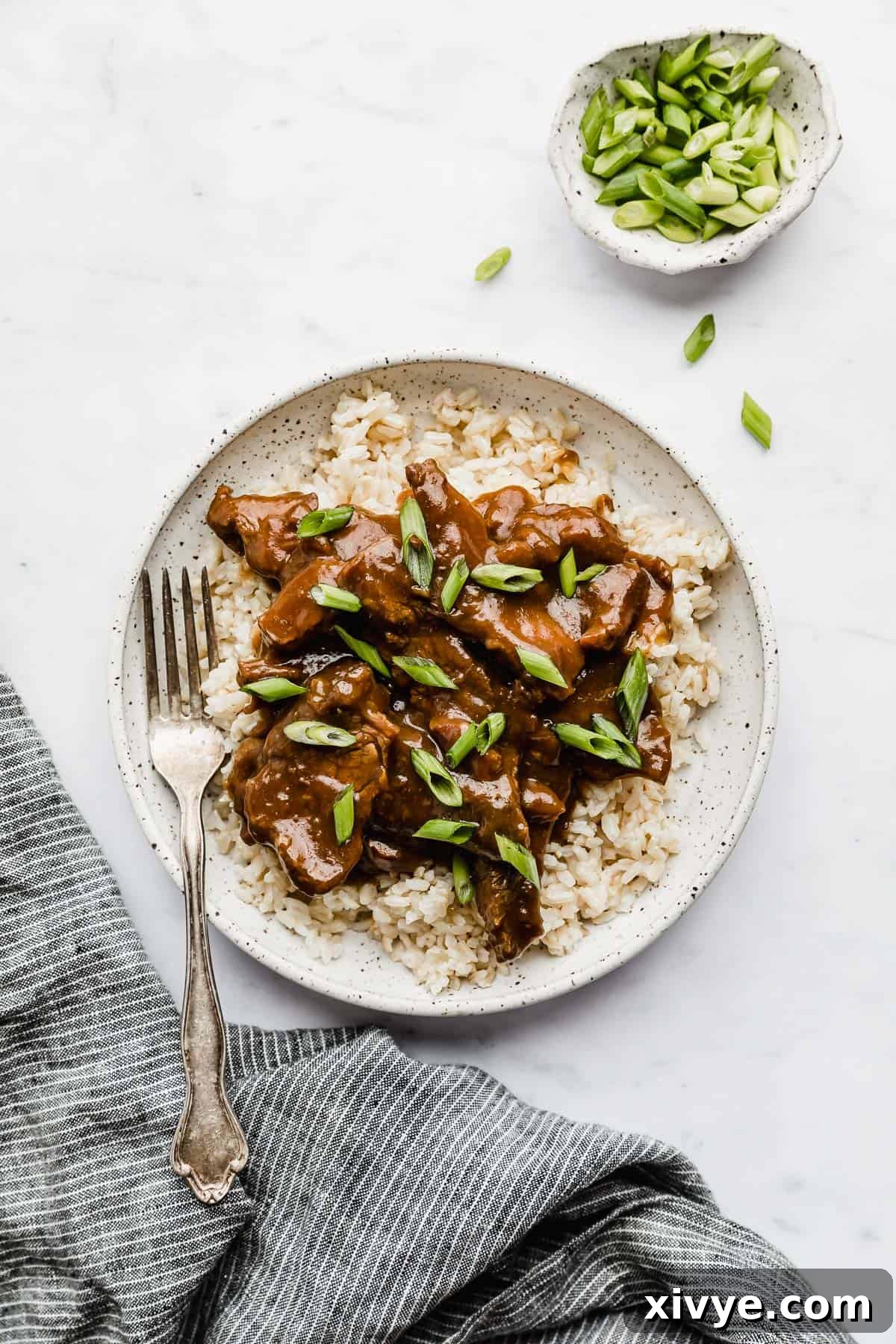 Slow Cooker Mongolian Beef on a plate topped with vibrant green onions, ready for a delicious meal.
