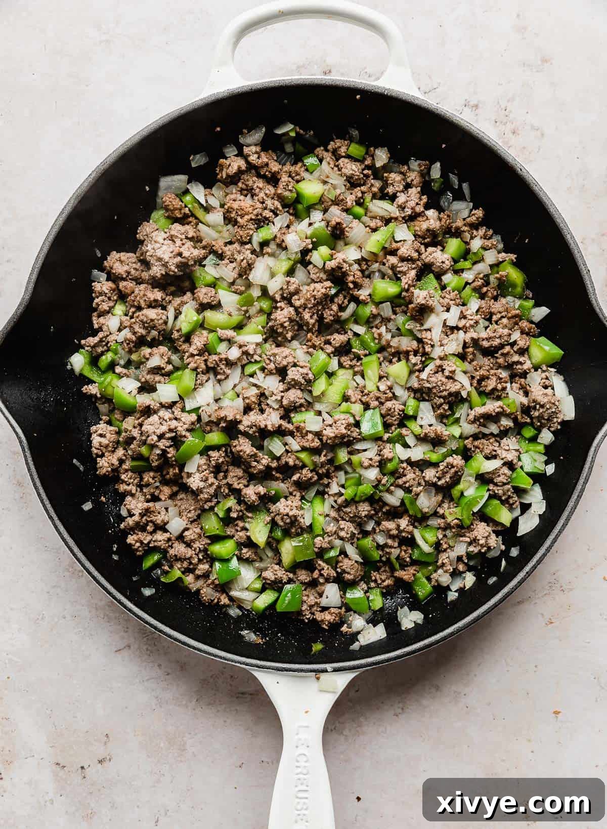 Philly Cheesesteak Joes 5 Perfectly browned ground beef mingled with tender chopped onion and green peppers, simmering together in a skillet, creating a fragrant base.