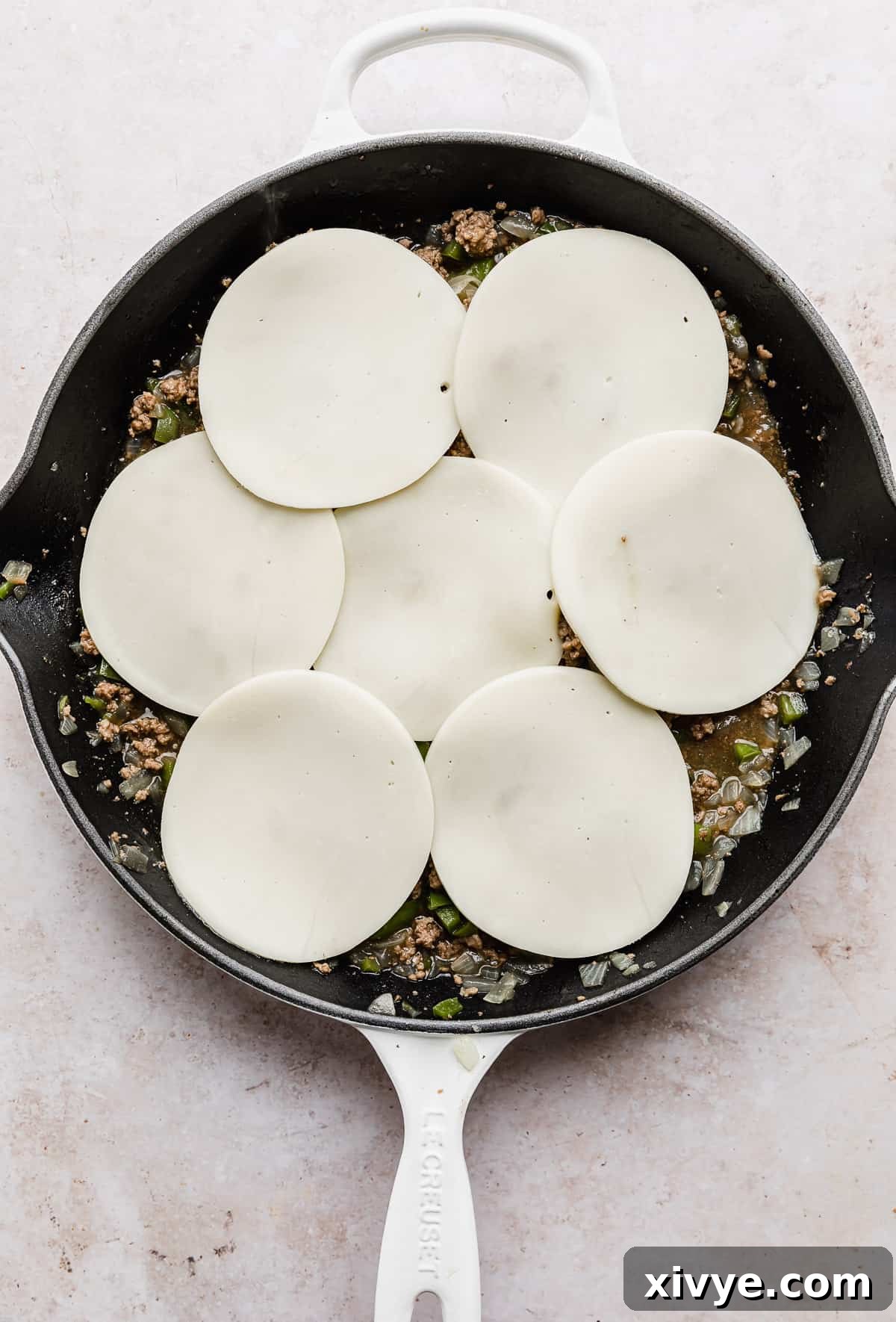 Philly Cheesesteak Joes 7 The irresistible sight of provolone cheese melting beautifully over the savory Philly Cheesesteak Sloppy Joes mixture, nestled in a white skillet.