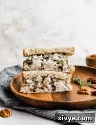 Leftover Turkey Salad on slices of bread that are cut in half, stacked on top of each other on a brown plate.