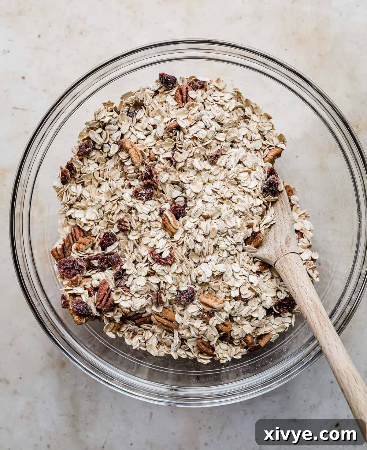 Festive Gingerbread Granola 5 A closer view of the dry ingredients for gingerbread granola, showcasing the mixture of oats, pecans, and dried cranberries in a glass bowl.