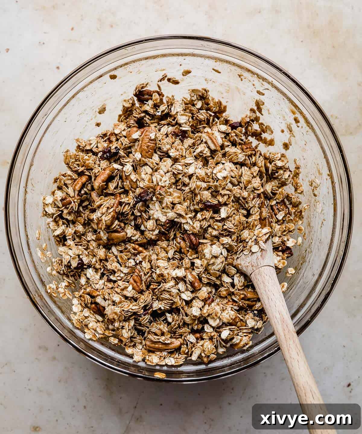 Festive Gingerbread Granola 9 Raw gingerbread granola mixture, vibrant with pecans and cranberries, evenly coated in a glass bowl.