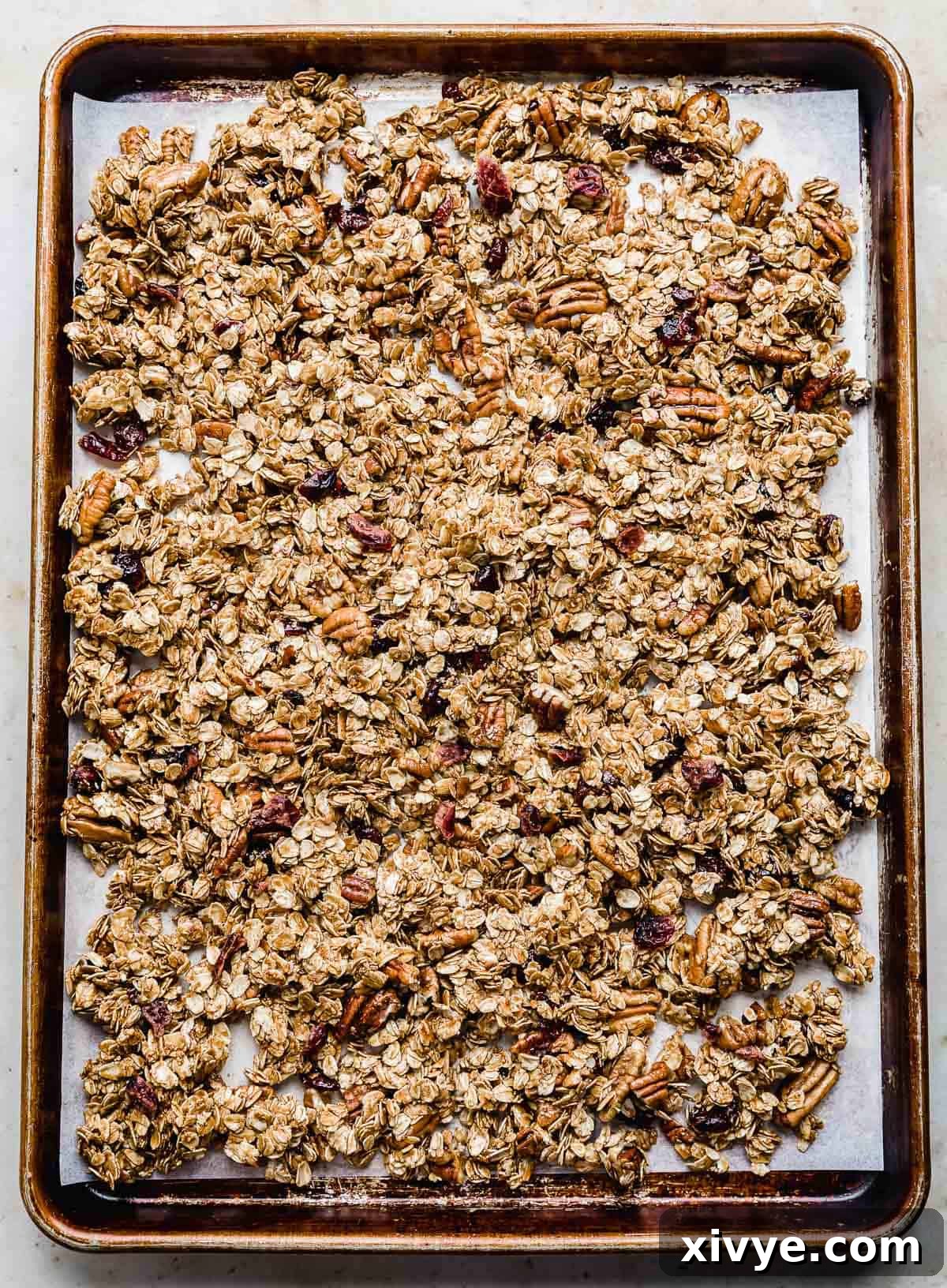 Festive Gingerbread Granola 10 The gingerbread granola mixture spread out evenly on a parchment-lined baking sheet, ready for the oven.