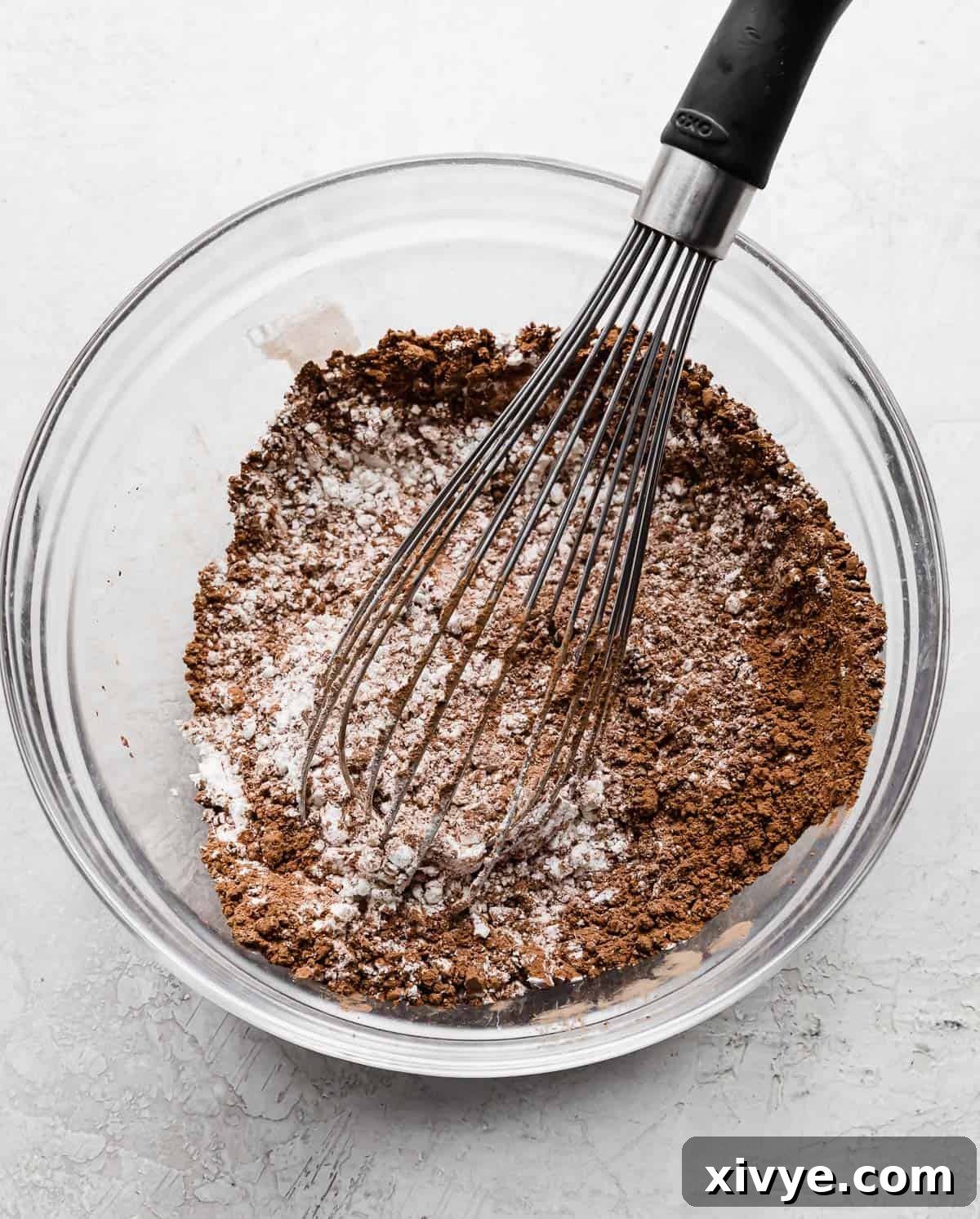 A whisk mixing a flour and cocoa powder for making chocolate orange cupcakes.