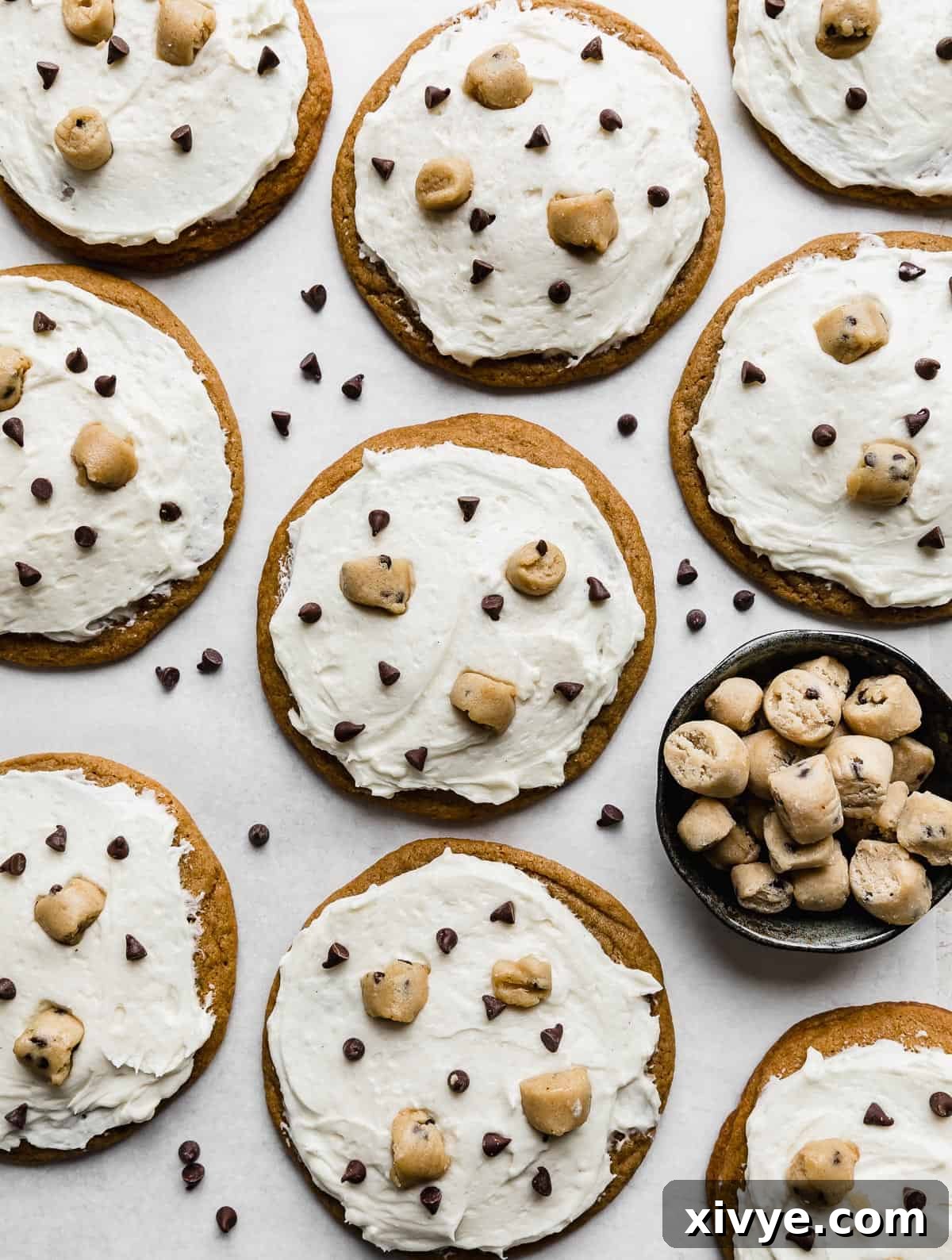 Brown sugar cookies topped with a white frosting, mini chocolate chips and cookie dough chunks.